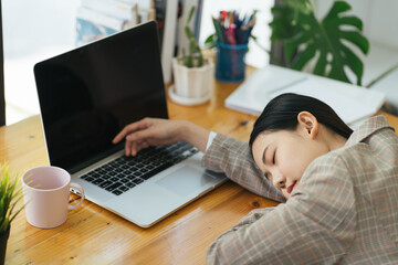 Overworked and tired businesswoman sleeping over a laptop in a desk at work in her office