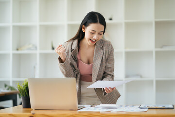 summary report, laptop and paper placed at office desk. Asian woman work online and plan financial data with laptop, work from home. Business woman and planner concept.