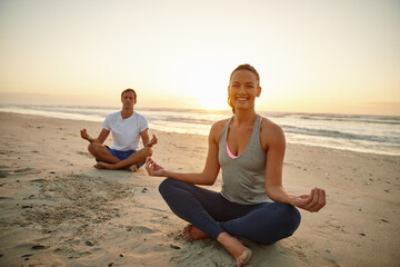 Fototapeta na wymiar Allow nature to restore you. Portrait of a couple doing yoga on the beach at sunset.
