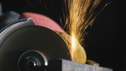 Forge workshop. Smithy manual production. Close up details of sparks, industrial worker using angle grinder and cutting steel. The blacksmith makes iron products for manufacture of fireplaces, stoves. © ivandanru