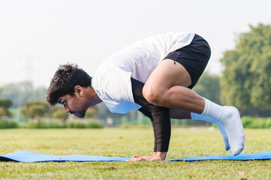 Young sportsman balancing on his hands, doing handstand in the park. young male working out early in the morning.
