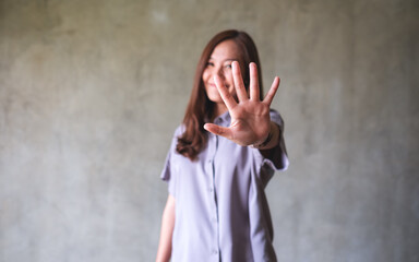 A young asian woman outstretched hand and showing stop hand sign