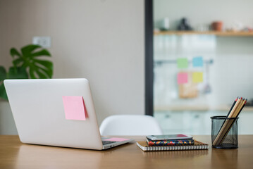 Working desk with laptop computer, document, paperwork, book, post-it and pencil. It is arranged neatly and decorated with plants to make it fresh.