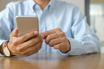 Businessman working with cell phone and looking information on cell phone at desk with copy space.