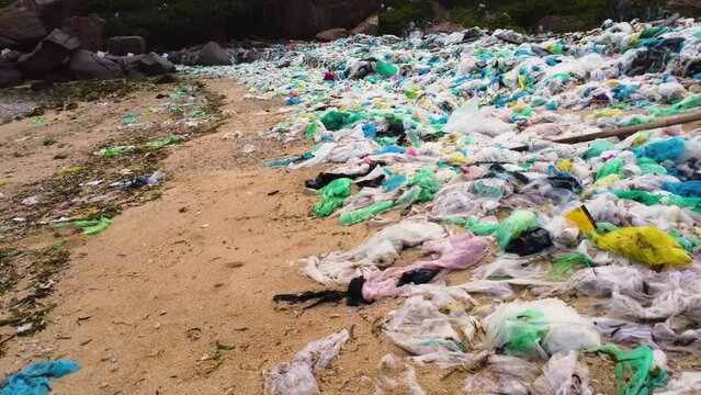 Sandy beach covered in plastic bags, environmental disaster; low aerial