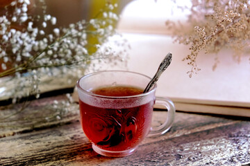 Brurred dry flowers on vintage notepad, cup of tea  on wooden table. Retro style, vintage toned