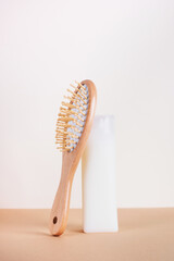 Still life with shampoo bottle and hair brush on beige background. Hair care concept, natural...