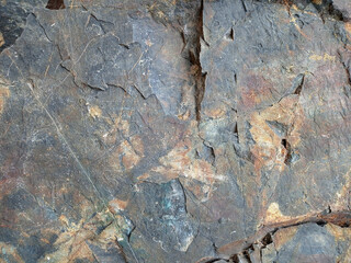 Stone mountains natural material background. Empty rough, uneven texture of a brown and gray concrete wall close up with copy space.