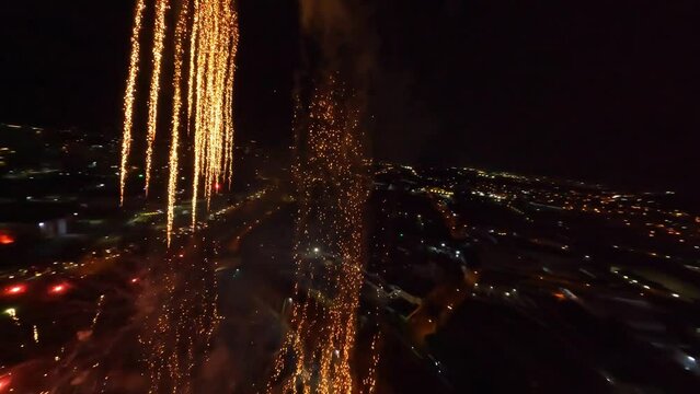 Dynamic drone flight through beautiful pyrotechnics during firework explosion at night 