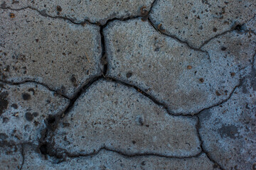 Texture of the dried earth. Dark gray background with cracks and hollows. Drought and lack of moisture in the soil. The consequences of abnormal heat. Environmental disaster. Global warming.