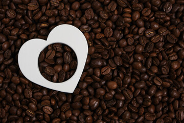 White heart on the background of roasted coffee beans.