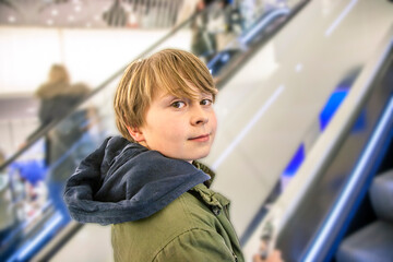 young boy on a moving staircase smiles confident