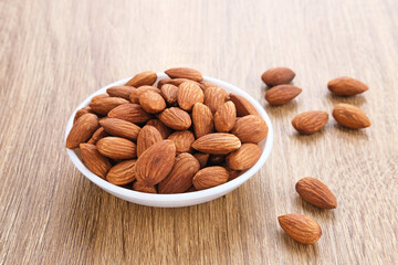 Almonds in bowl on wooden table.  Close up. Selected focus

