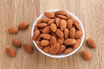 Almonds in bowl on wooden table.  Close up. Selected focus
