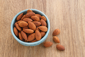 Almonds in bowl on wooden table.  Close up. Selected focus
