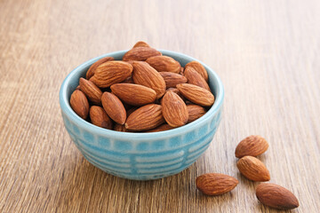 Almonds in bowl on wooden table.  Close up. Selected focus
