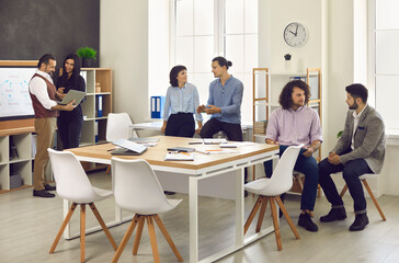 Different business people meet up in modern workplace or coworking office space. Company employees working together, discussing projects, sharing ideas and collaborating