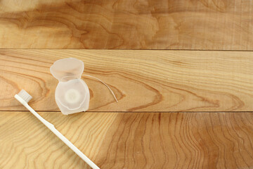 Toothbrush and dental floss on a wooden table