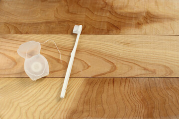 Toothbrush and dental floss on a wooden table
