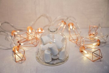 marshmallows in a glass bowl against the background of a luminous garland