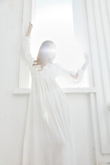 Fototapeta na wymiar Woman in white dress near window posing romance of the sun