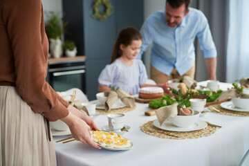Caucasian woman putting a plate with eggs on the easter table