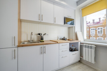 Interior of the small living equipped kitchen in studio apartments in minimalistic style with light color