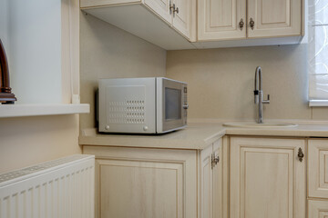 Fototapeta premium Interior of the small living equipped kitchen in studio apartments in minimalistic style with light color