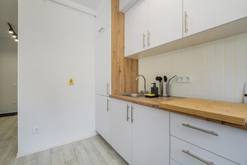 Interior of the small living equipped kitchen in studio apartments in minimalistic style with light color