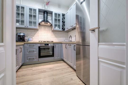 Interior of the small living equipped kitchen in studio apartments in minimalistic style with light color