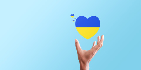 Hand holding Ukraine flag in the shape of heart. Russian-Ukrainian conflict. National security society, prevention of war in Ukrain
