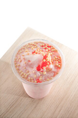Strawberry smoothie with toppings in a plastic cup.
