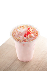 Strawberry smoothie with toppings in a plastic cup.