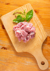 Raw pork minced pork on a wooden chopping board and basil leaves