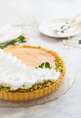 Grapefruit tart with whipped cream and pistachios on marble background.