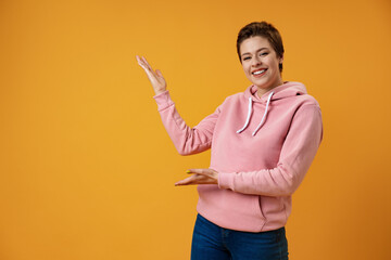 Young woman with short hair over studio color background pointing finger to the side