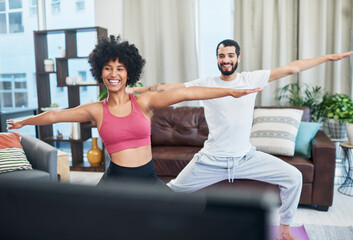 We learned everything we know from this video. Shot of a couple looking at the television while practising yoga at home.