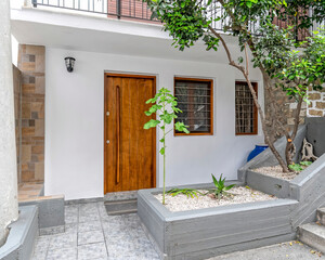 simple white house facade with brown natural wood door and windows