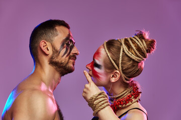 Beautiful young acrobats or gymnasts with colorful face painting on pink blue gradient background....