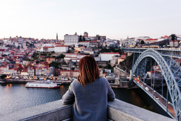 Fototapeta na wymiar back view of relaxed woman in Porto bridge at sunset. Tourism in city Europe. travel and lifestyle