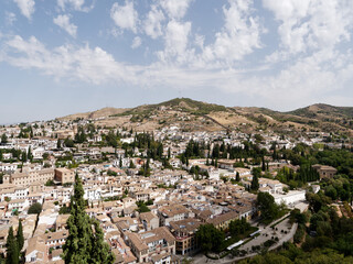 Fototapeta na wymiar Panoramic view of the city of Granada in Spain. Old and multicultural town. Sunny day, blue sky and some clouds. Heritage Spain. 