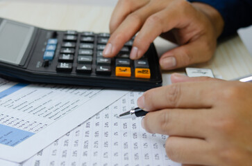 Man hand holding a pen and a calculator making financial plans Tax and business investment.