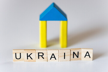 Napis Ukraina, w tle domek z drewnianych klocków w barwach narodowych Ukrainy