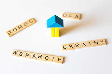 Pomoc wsparcie dla Ukrainy - słowa z literek przy drewnianym domku w barwach narodowych Ukrainy