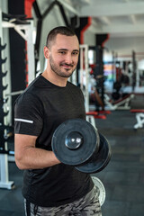 Fototapeta na wymiar caucasian man doing workout with dumbbells in gym