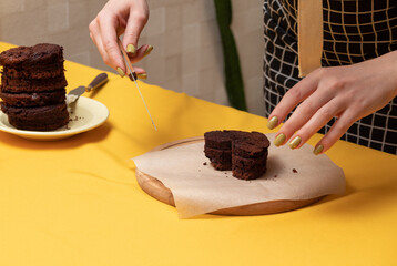 There are three biscuits for bento cake on wooden board. Women's hands hold pruning knife. Making dessert at home. Selective focus.