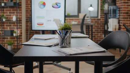 Close up of meeting table and monitor in business office. Nobody in startup space with empty desk and charts presentation, modern decor used for company work in professional boardroom.