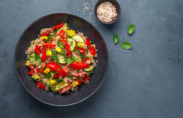 Salad with quinoa, tomatoes, cucumber, avocado and red pepper on a gray-blue background.