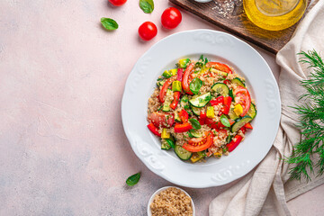 Fresh salad with quinoa, avocado, tomatoes and cucumber and herbs on a light background.