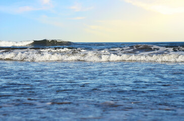 Waves at sea on sunset background. Waves at sea during storm and wind. Wave from the sea goes on...